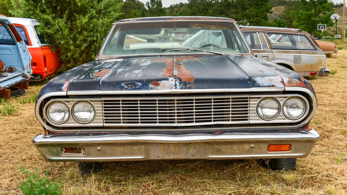 A rusting car left behind in a junk yard