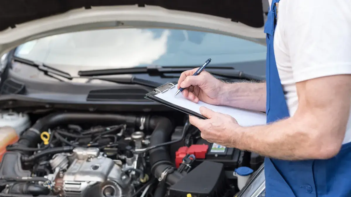 A technician checking a car engine after repairs