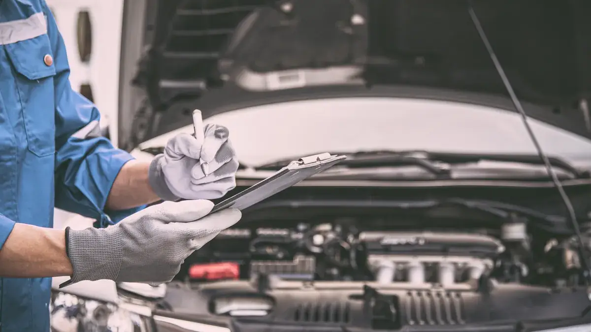 A technician completing an inspection checklist on a car engine
