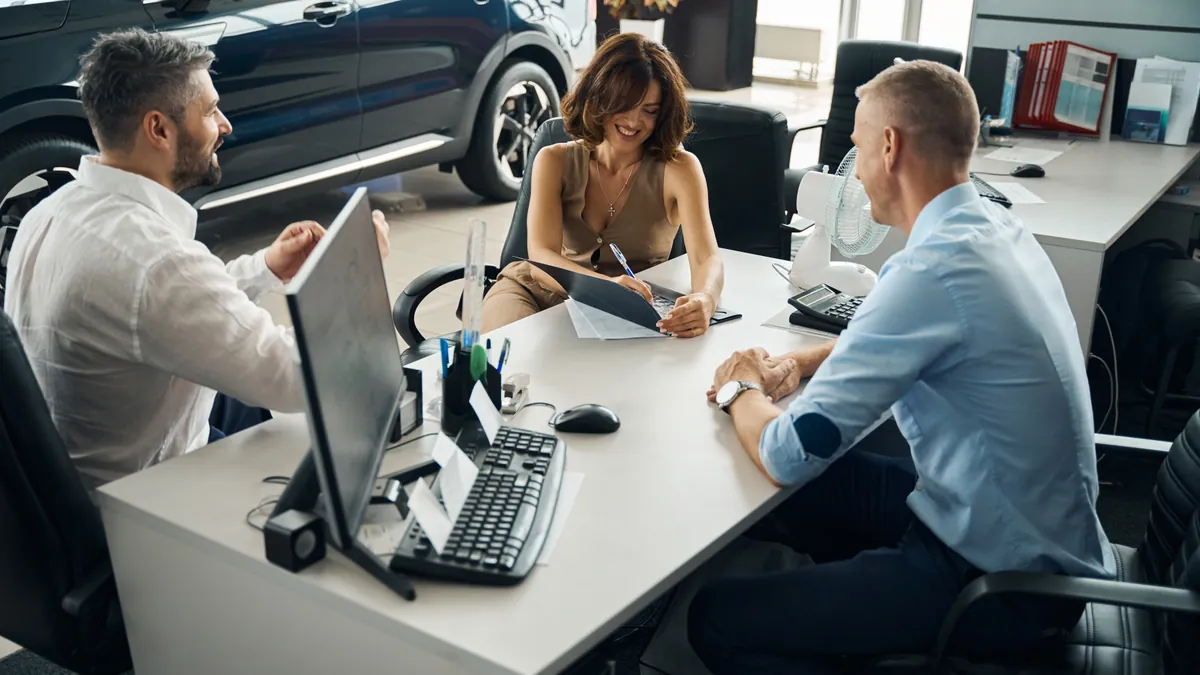 A couple completing lease paperwork in a showroom