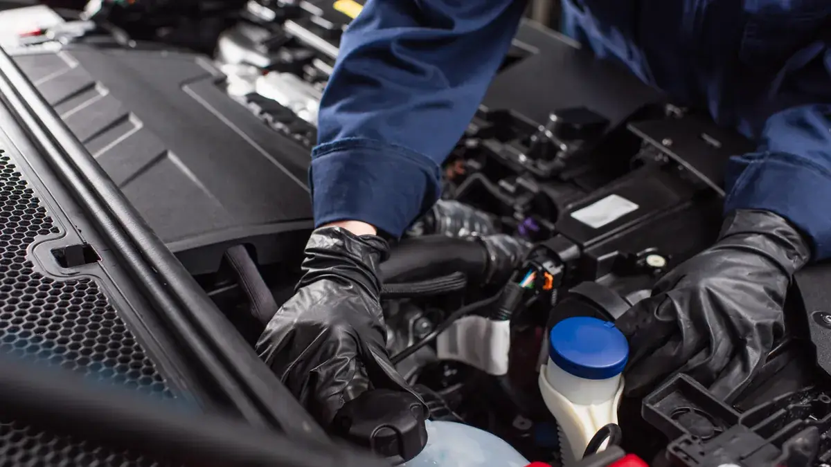 A mechanic working on a damaged vehicle's engine bay