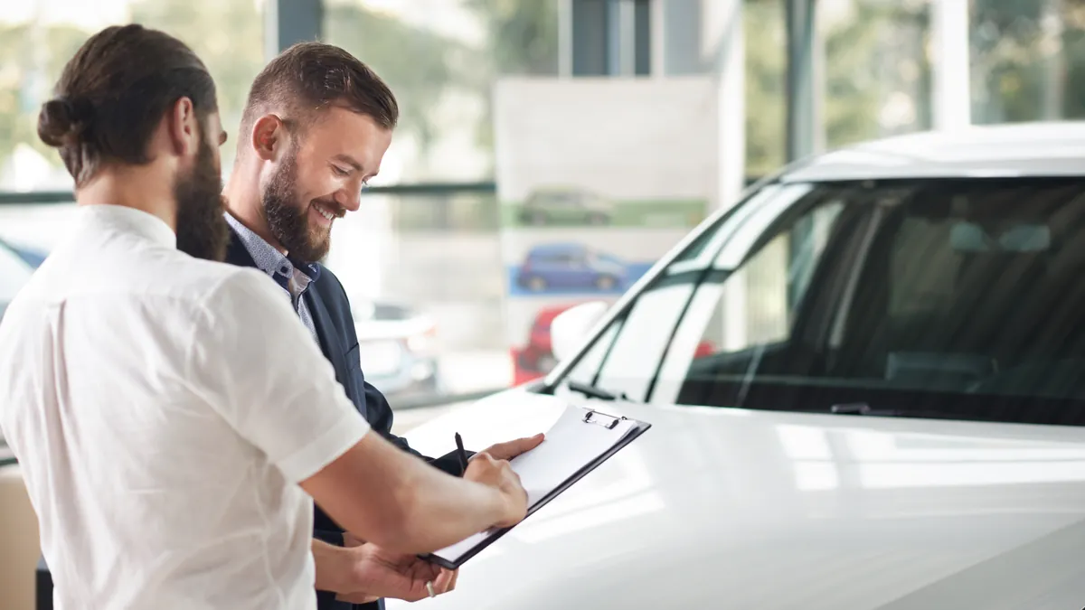 A seller signing vehicle paperwork on a folder