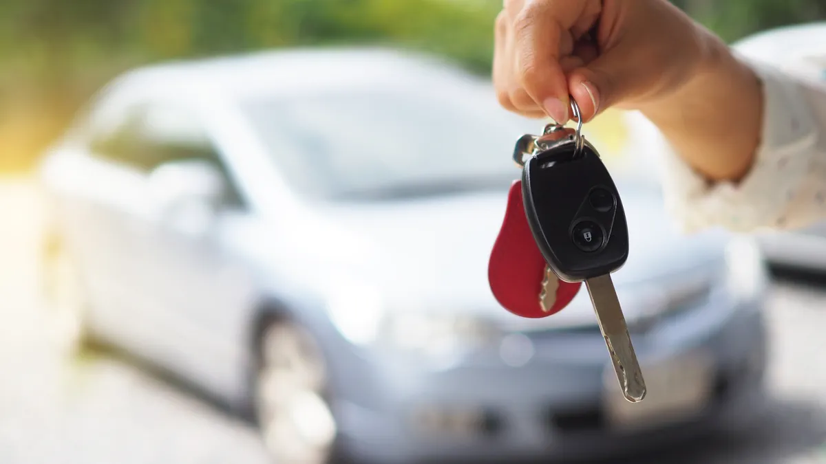 An owner handing the car keys to the new buyer after a title transfer